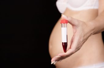 A pregnant woman holds a test tube of blood in front of her. Pregnancy, blood control in the laboratory.